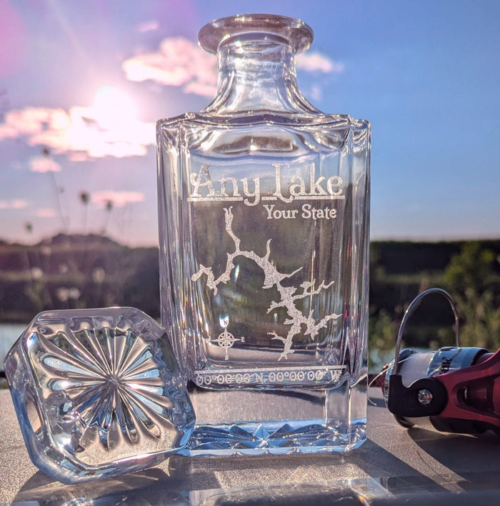 Lifestyle photo: engraved whiskey decanter with a sample lake design, outdoors under a bright sky