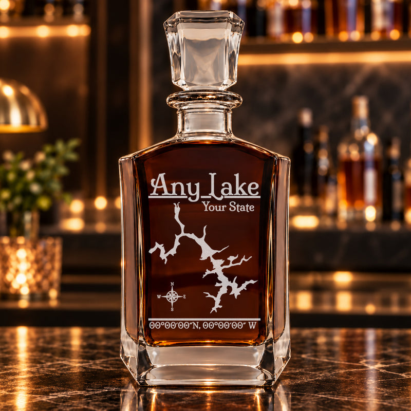 Classic six-sided decanter alone with frosted generic lake artwork, amber whiskey, and a warm bar background.