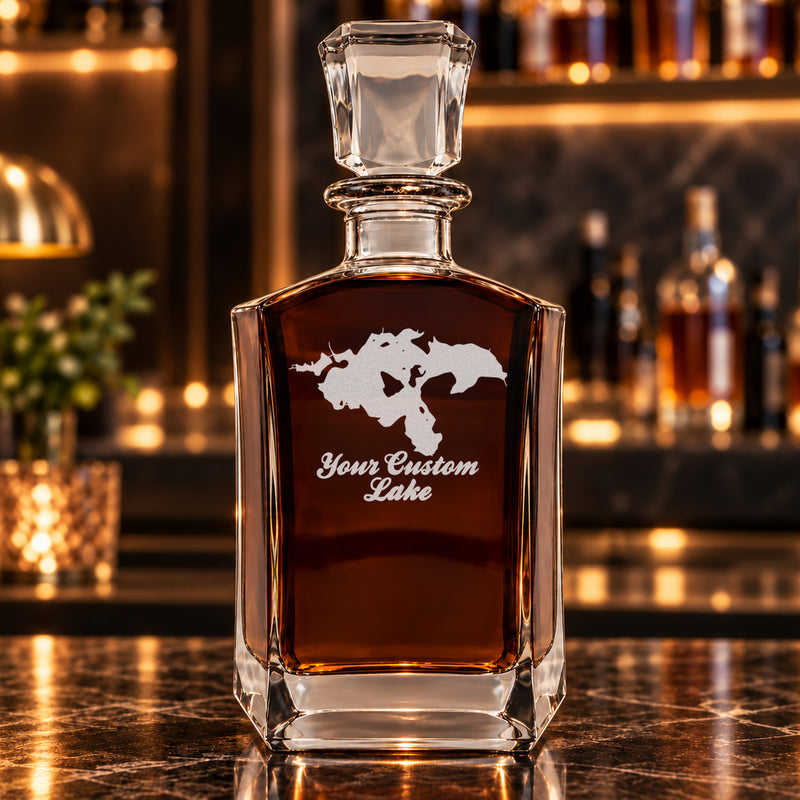 Minimalist six-sided decanter alone with frosted generic lake artwork, amber whiskey, and a warm bar background.