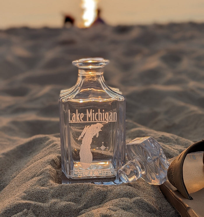 Lifestyle photo: Lake Michigan engraved whiskey decanter in beach sand at sunset