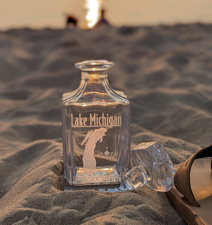 Lifestyle photo: Lake Michigan engraved whiskey decanter in beach sand at sunset